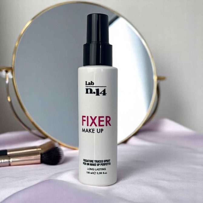 Spray fissante trucco Lab N14 da 100 ml su fondo rosa con specchio e pennello make-up